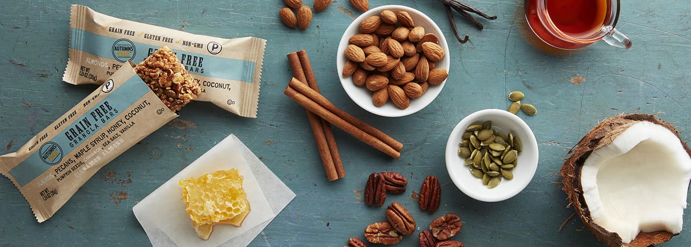 Autumn's Gold granola bars with bowls of almonds and pumpkin seeds, cinnamon sticks and honey comb