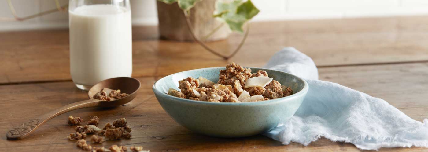 A bowl of Autumn's Gold Toasted Coconut Almond grain free granola in a bowl with a bottle of milk